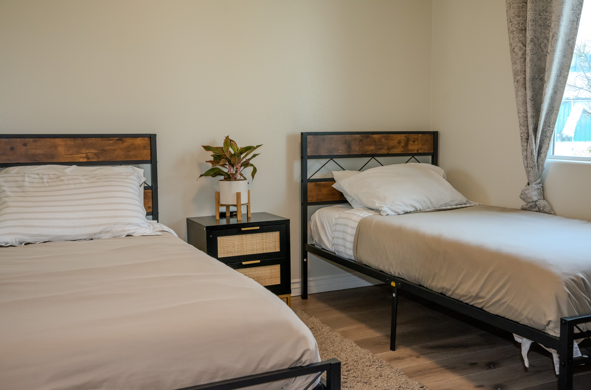 Shared bedroom at Fresh Start of California, featuring two twin beds with modern wood-accented frames, neutral bedding, and a calming, minimalist design.